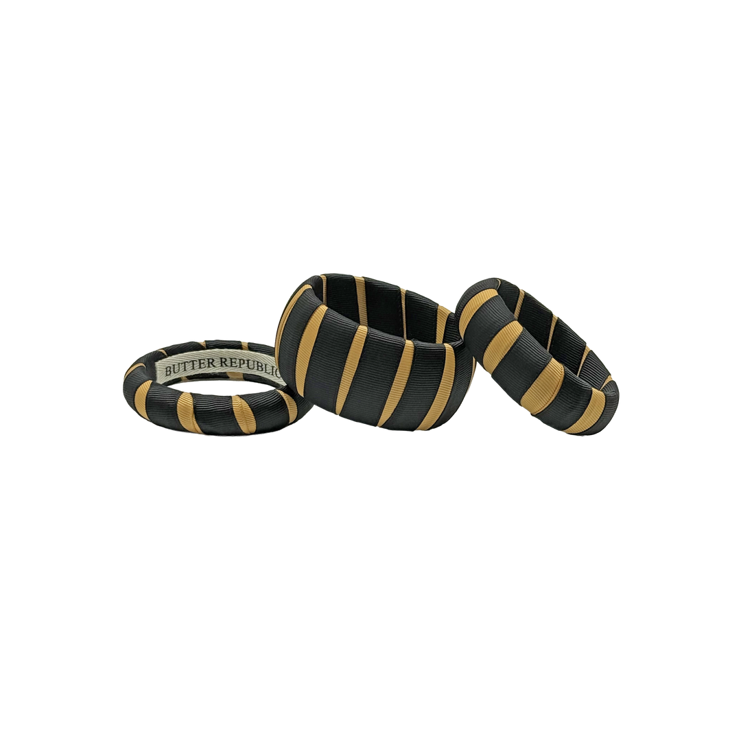 three multi-sized black and gold  Butter Republic classic bracelets with logo brand label on the interior of the bracelet