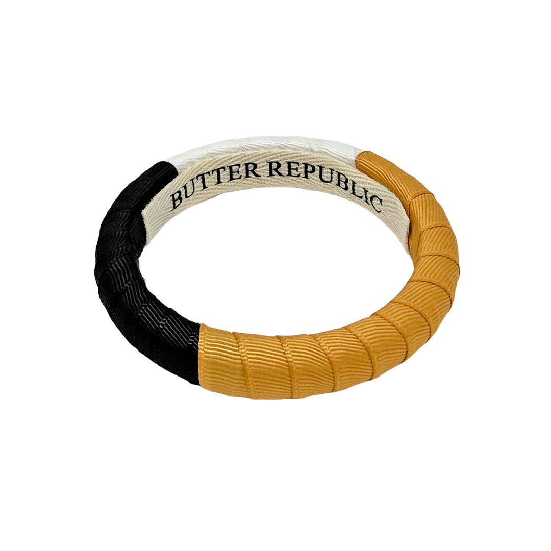 Black, gold, and white Butter Republic bracelet with brand label on the interior 
