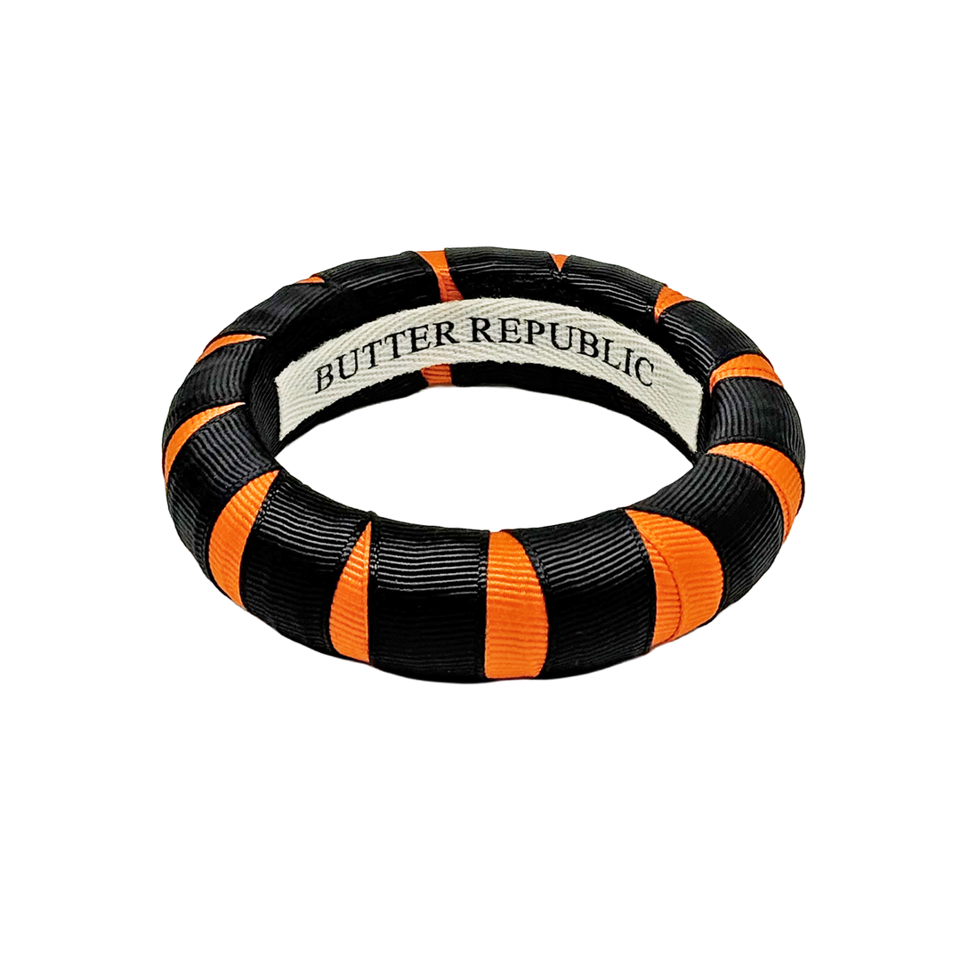 A black and orange Butter Republic bangle bracelet