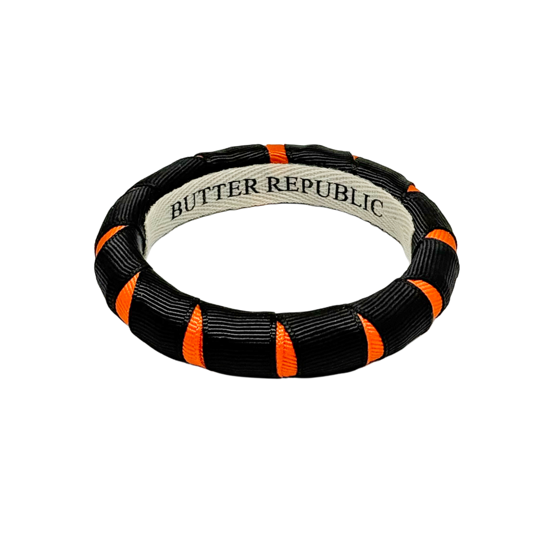 A black and orange Butter Republic narrow bangle bracelet