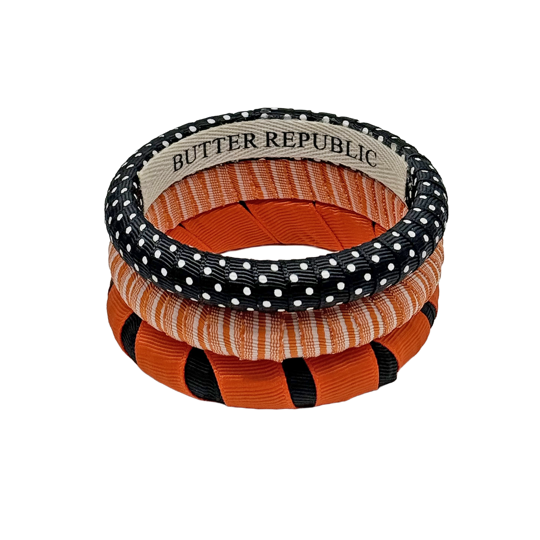 A stack of three Butter Republic orange and black bracelets