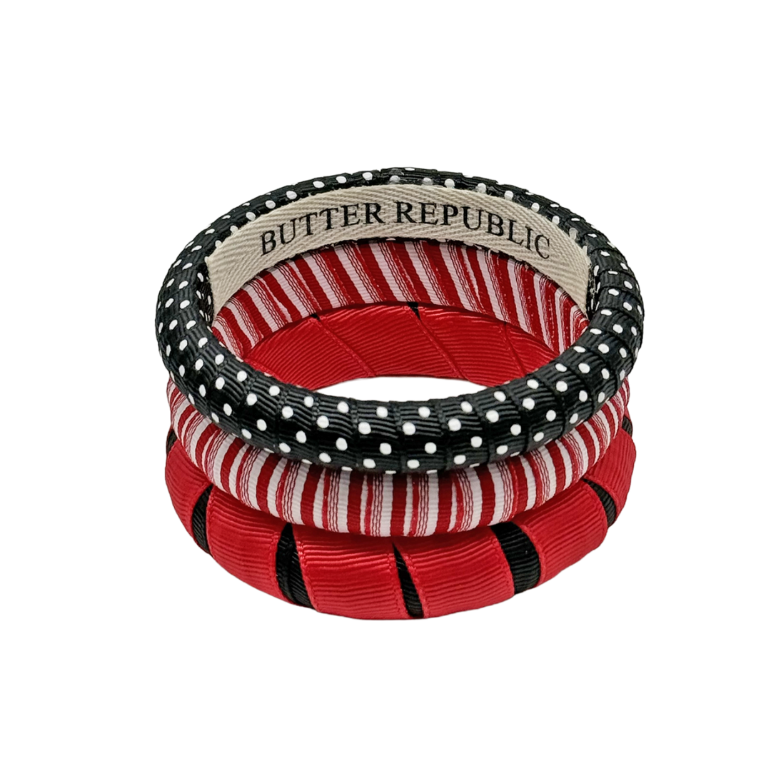 three red and black Butter Republic bracelets stacked, with logo brand label on the interior