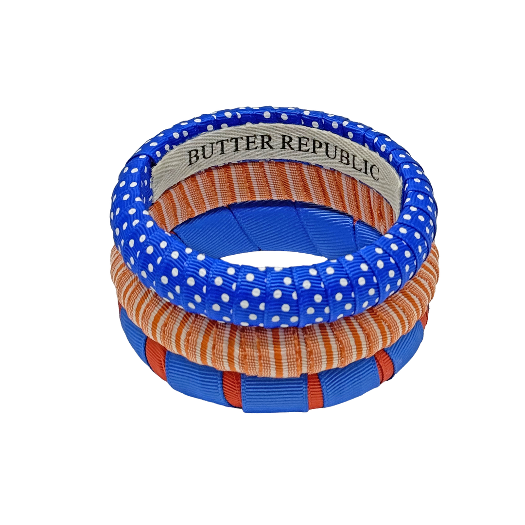stack of three orange and blue Butter Republic bracelets with logo brand label on the interior of the bracelet
