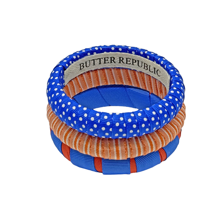 stack of three orange and blue Butter Republic bracelets with logo brand label on the interior of the bracelet
