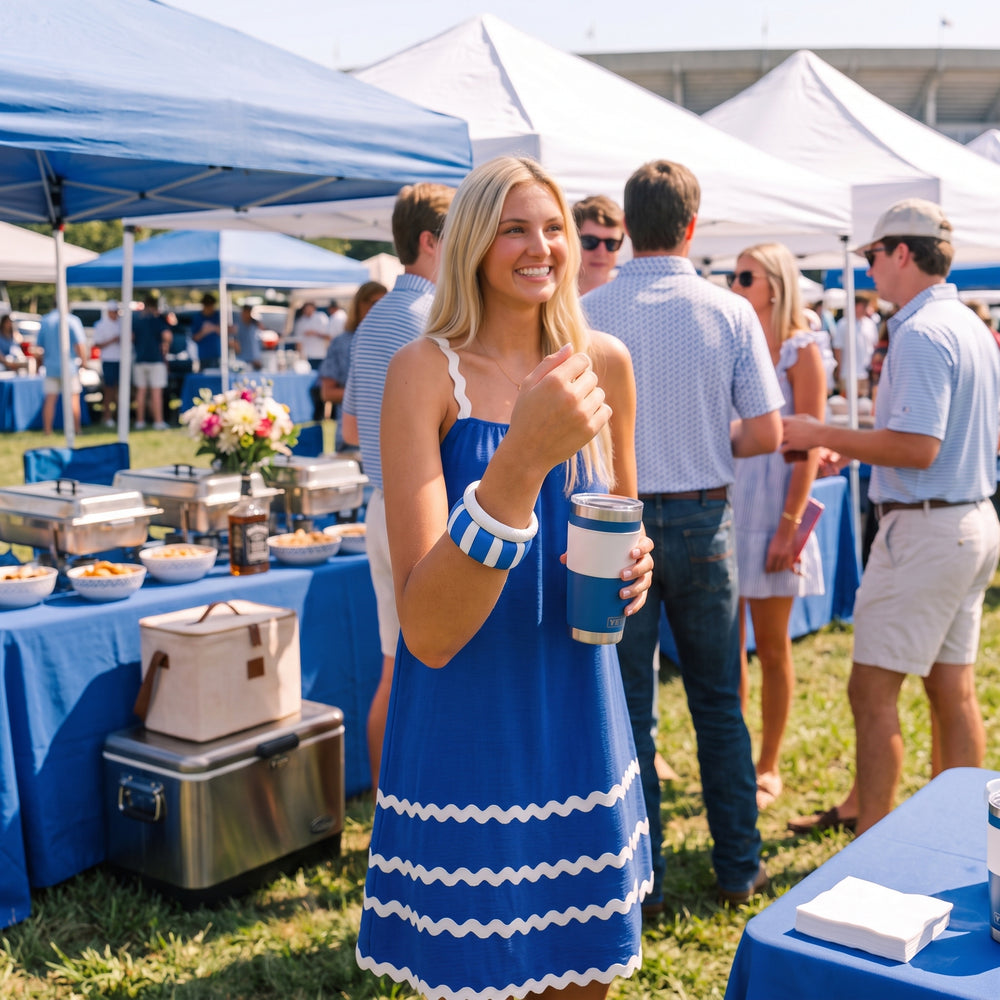A young woman at a blue and white-themed tailgate gathering wearing a wide blue and white Butter Republic bangle bracelet