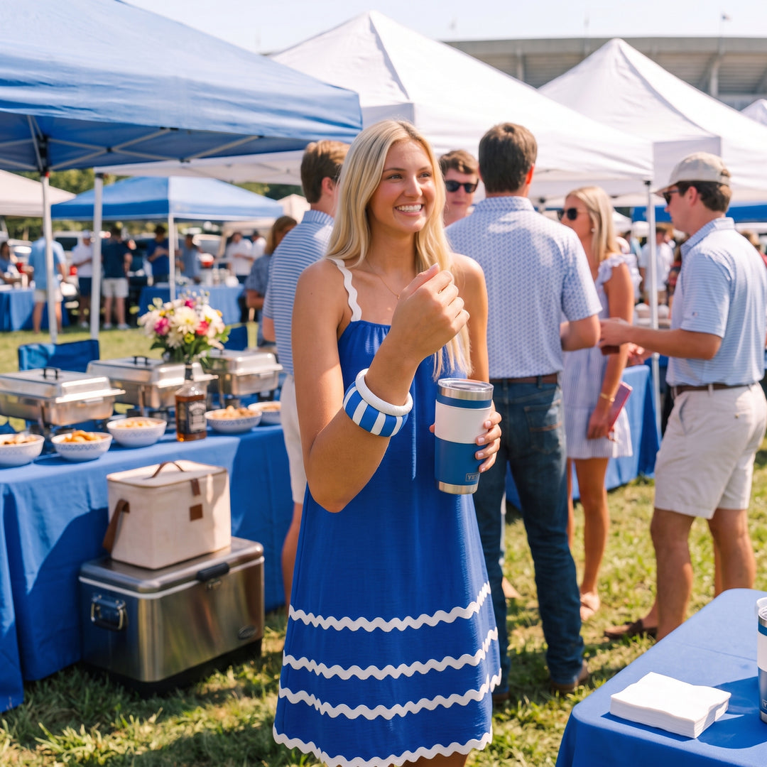 A young woman at a blue and white-themed tailgate gathering wearing a wide blue and white Butter Republic bangle bracelet