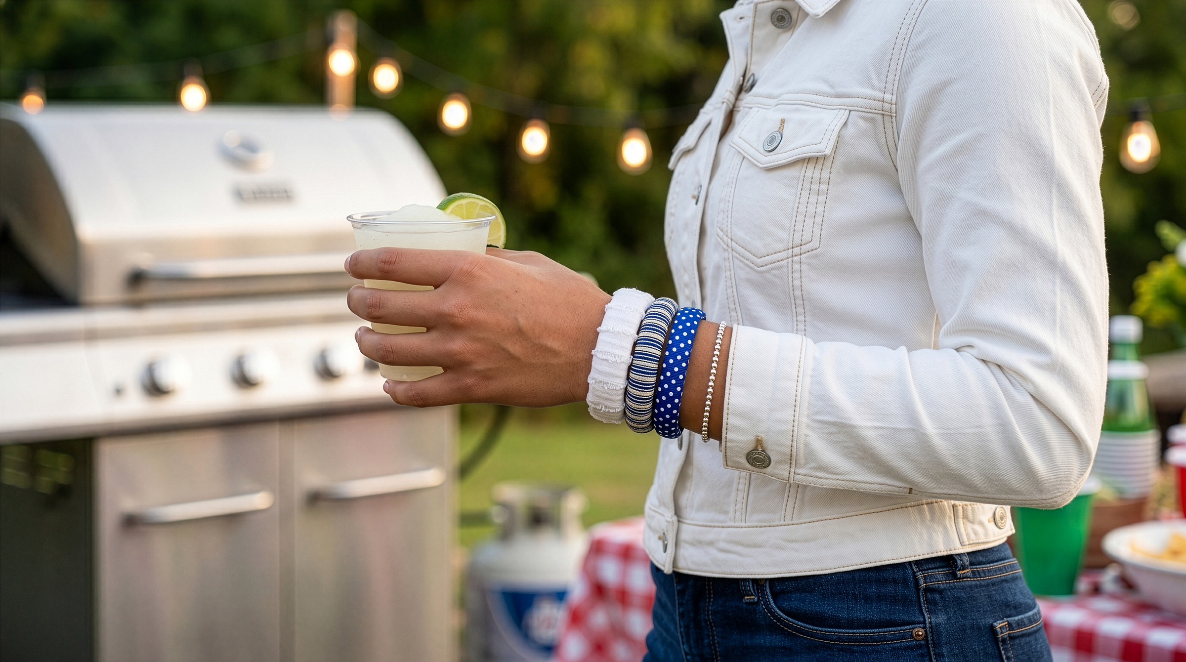 woman outdoors in front of a grill, wearing  three blue and white Butter Republic bracelets