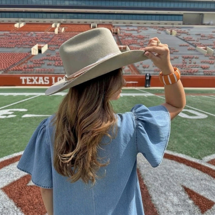 woman wearing a cowboy hat and a burnt orange and white Butter Republic bracelet in a football stadium