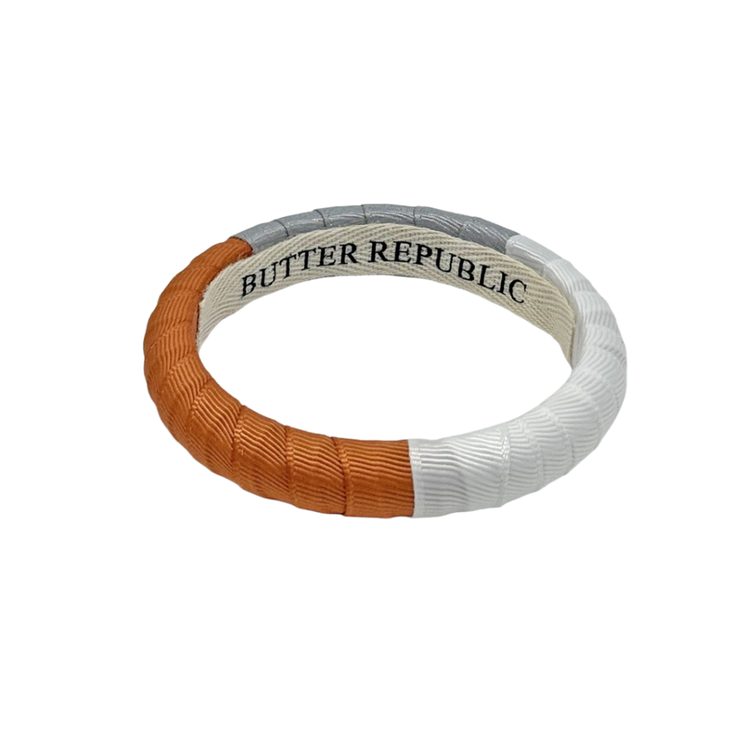 burnt orange, gray, and white color block Butter Republic bracelet with logo brand label on the interior of the bracelet