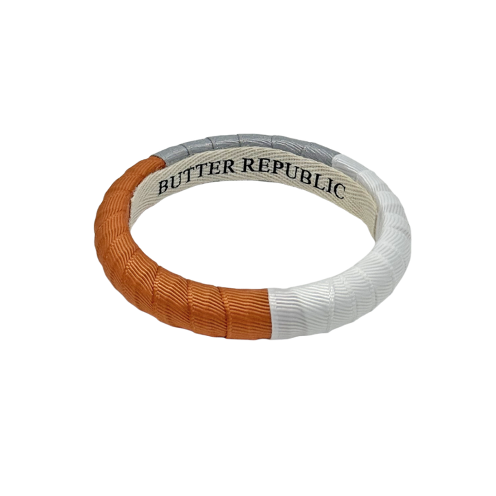 burnt orange, gray, and white color block Butter Republic bracelet with logo brand label on the interior of the bracelet