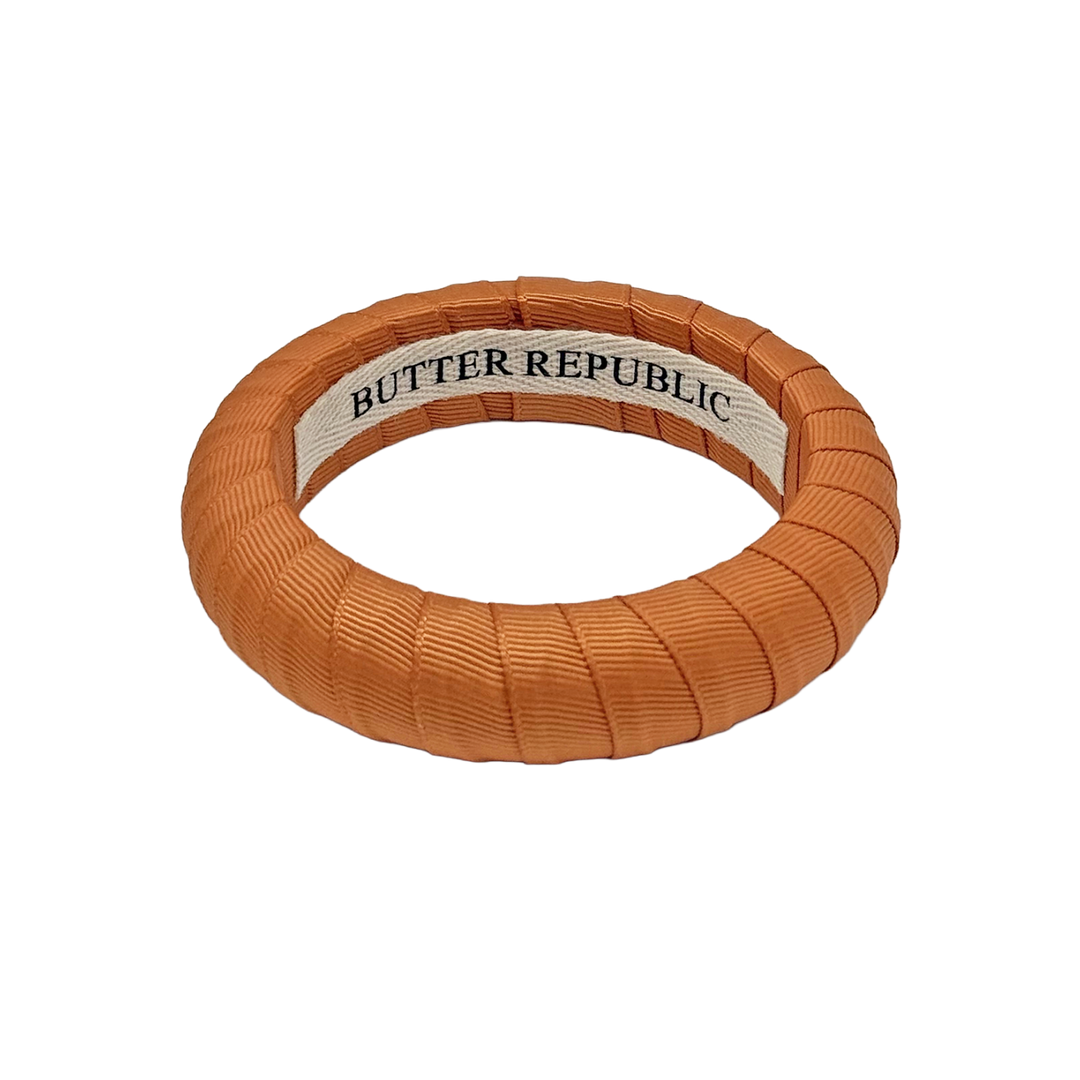 burnt orange Butter Republic bracelet with logo brand label on the interior of the bracelet