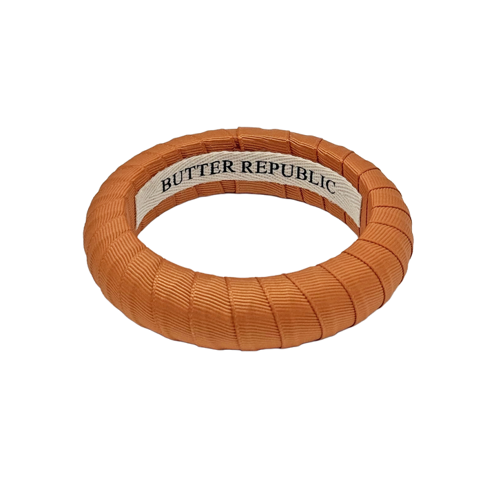burnt orange Butter Republic bracelet with logo brand label on the interior of the bracelet