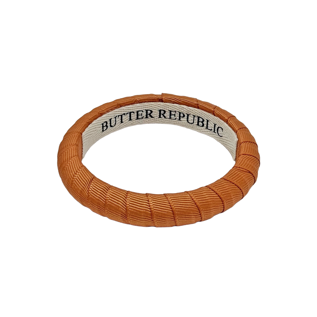 burnt orange Butter Republic bracelet with logo brand label on the interior of the bracelet
