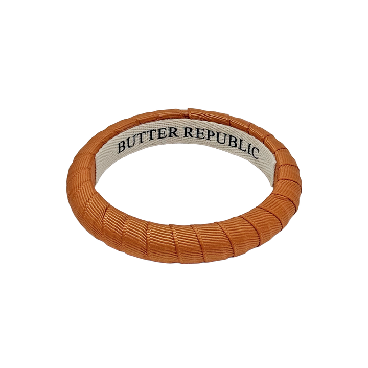 burnt orange Butter Republic bracelet with logo brand label on the interior of the bracelet