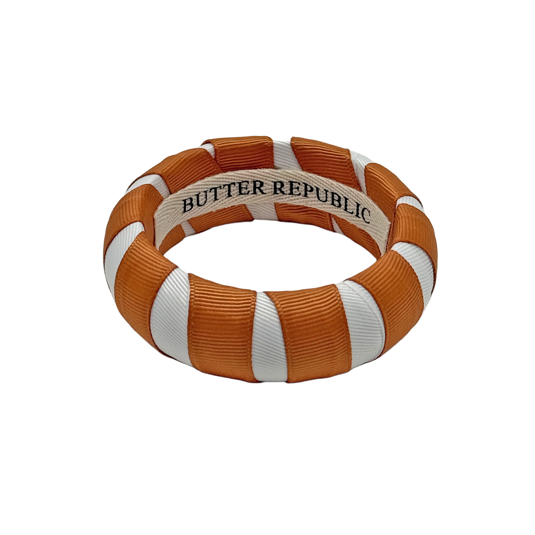 burnt orange and white Butter Republic bracelet with logo brand label on the interior of the bracelet