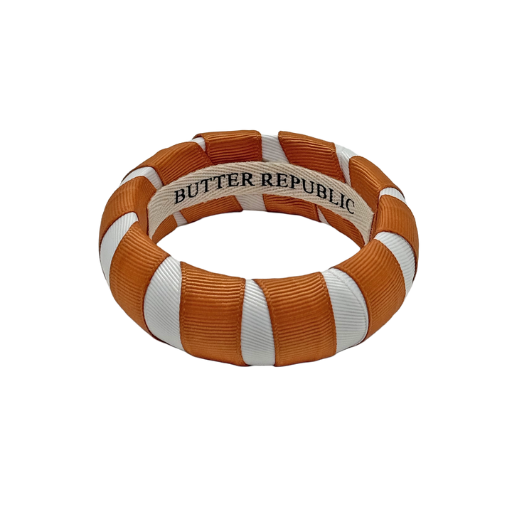 burnt orange and white Butter Republic bracelet with logo brand label on the interior of the bracelet