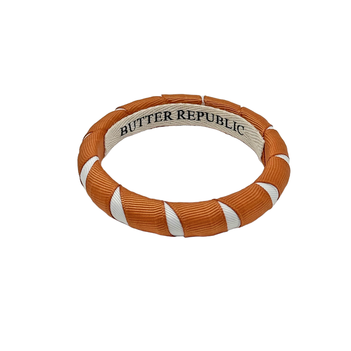 burnt orange and white Butter Republic bracelet with brand logo label on the interior of the bracelet