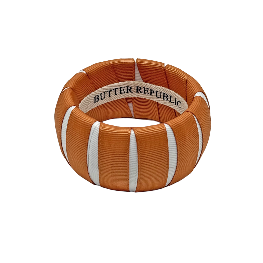 burnt orange and white Butter Republic bracelet with logo brand label on the interior of the bracelet