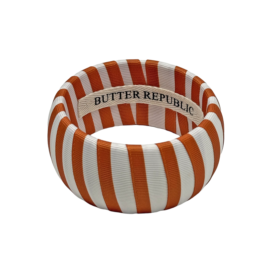 burnt orange and white striped Butter Republic bracelet with logo brand label on the interior of the bracelet