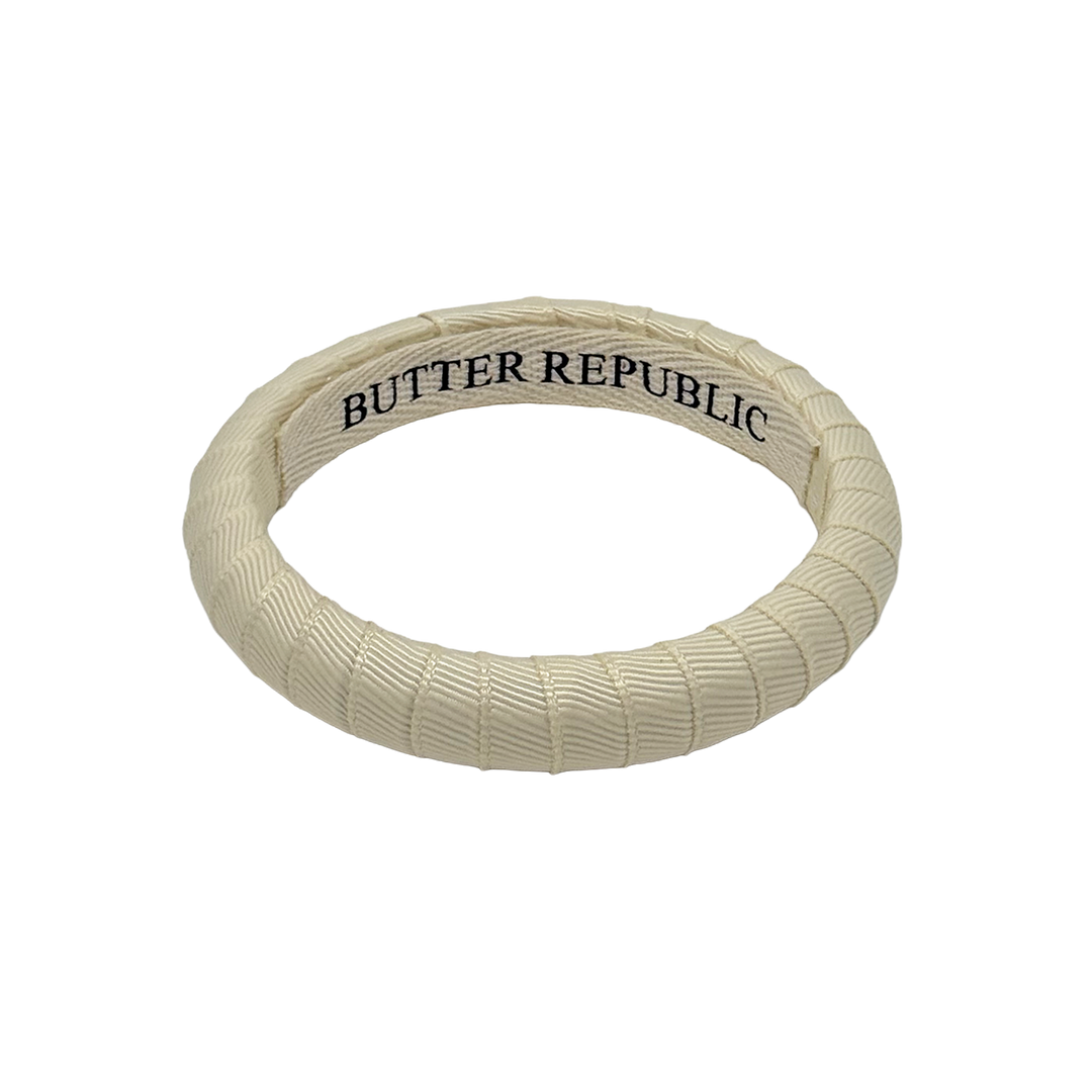 cream colored Butter Republic bracelet with brand label on the interior