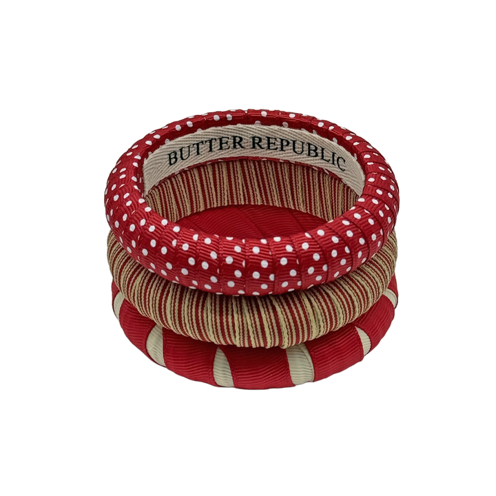 three crimson and cream Butter Republic bracelets stacked with logo brand label on the interior of the bracelet