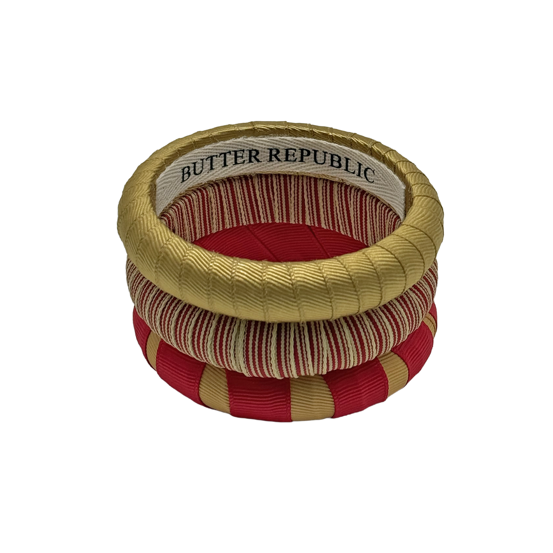 stack of crimson and gold Butter Republic bracelets with logo brand label on the interior of the bracelet