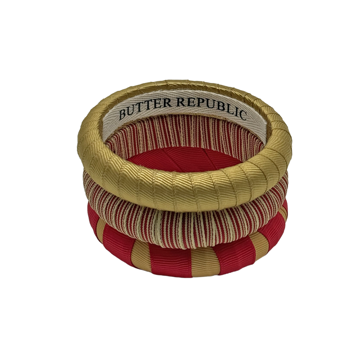 stack of crimson and gold Butter Republic bracelets with logo brand label on the interior of the bracelet