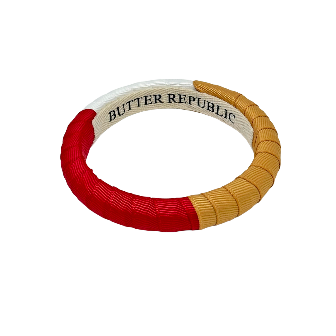 Red, gold, and white color block bracelet with Butter Republic brand label on the interior