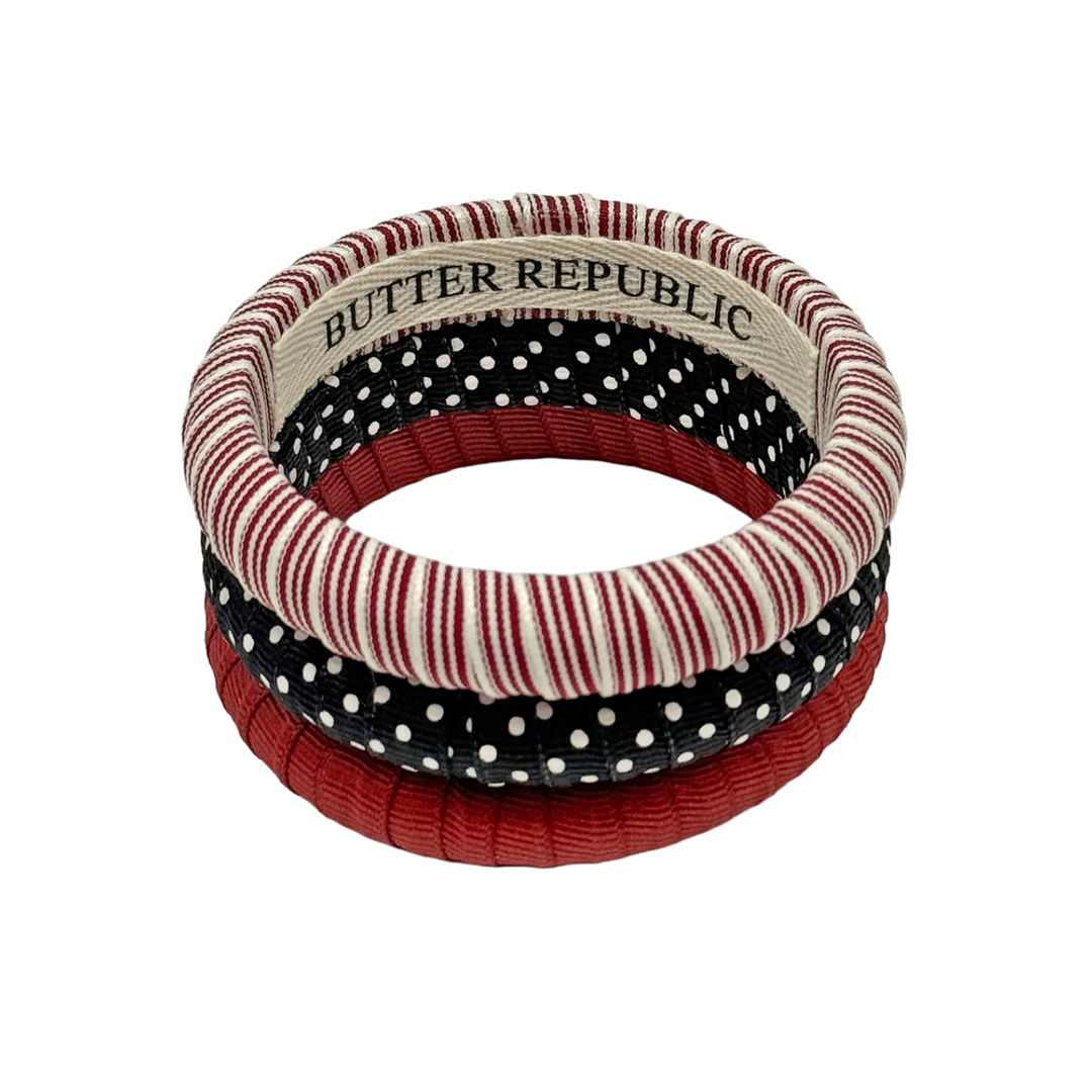 Assorted garnet, black, and white Butter Republic bracelets with brand label on the interior