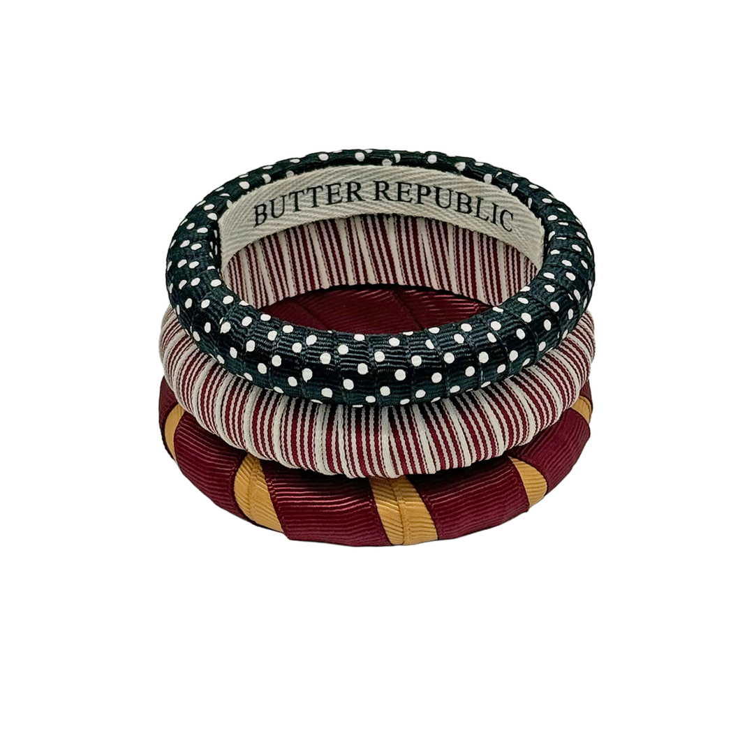 Set of three garnet, gold, black, and white Butter Republic bracelets, with brand label on the interior