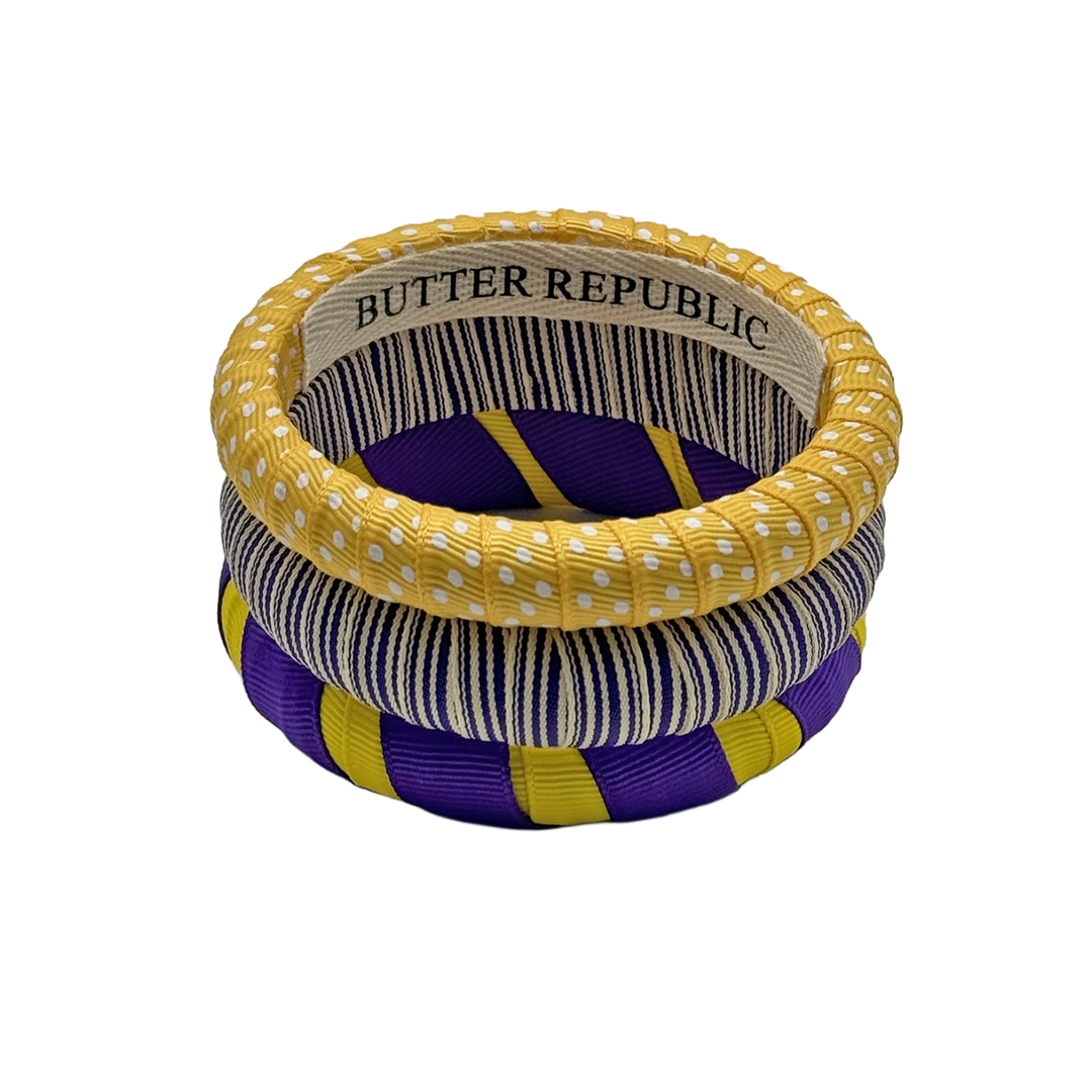 set of purple and gold Butter Republic bracelets with logo brand label on the interior