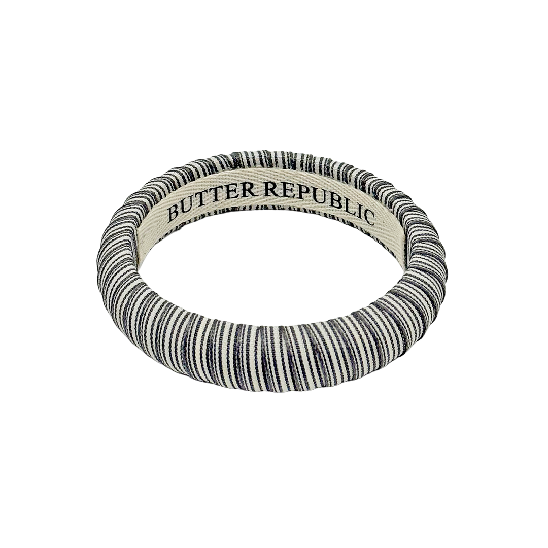 gray and white pinstripe Butter Republic bracelet with logo brand on the interior of the bracelet