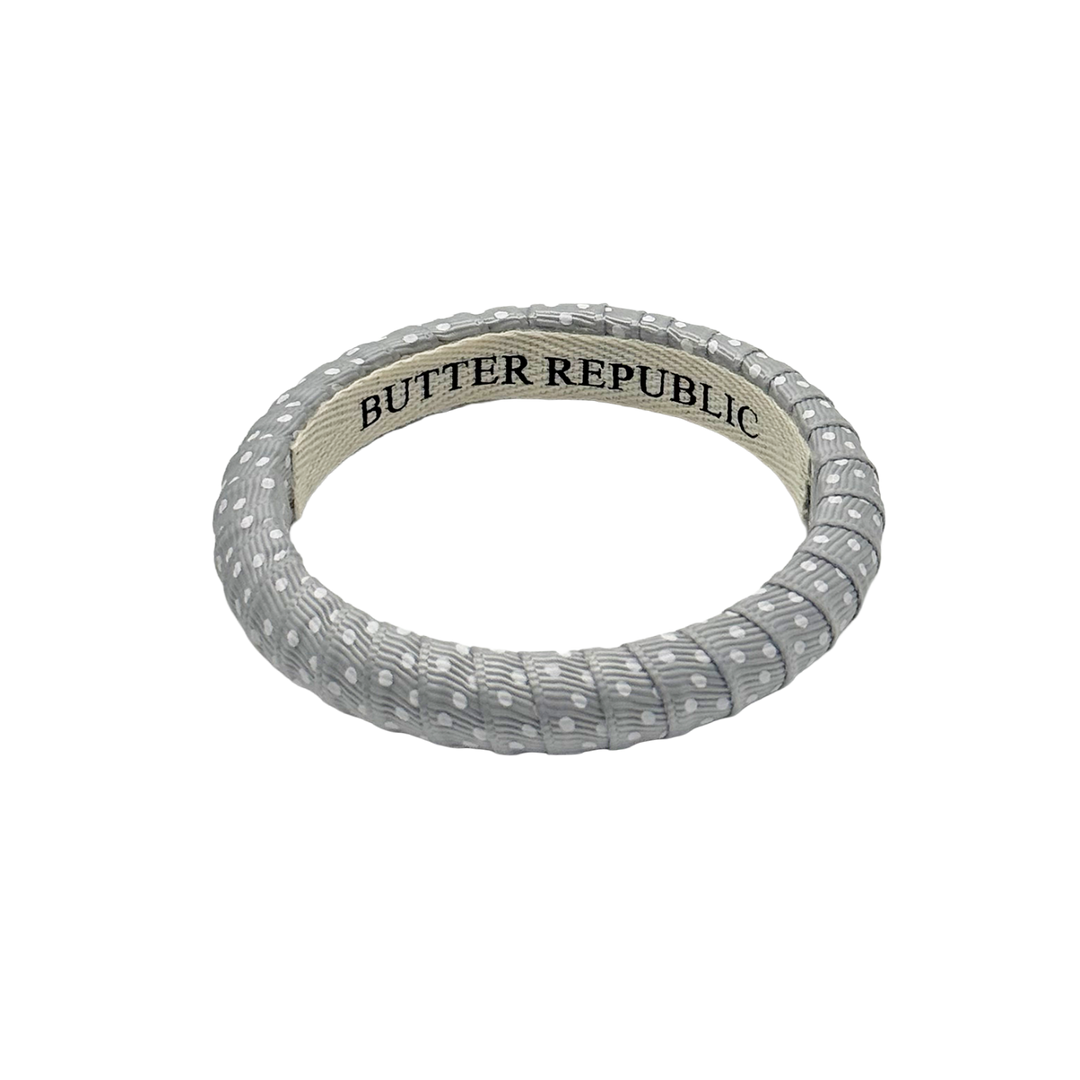 gray and white Swiss dot Butter Republic bracelet with logo brand on the interior of the bracelet