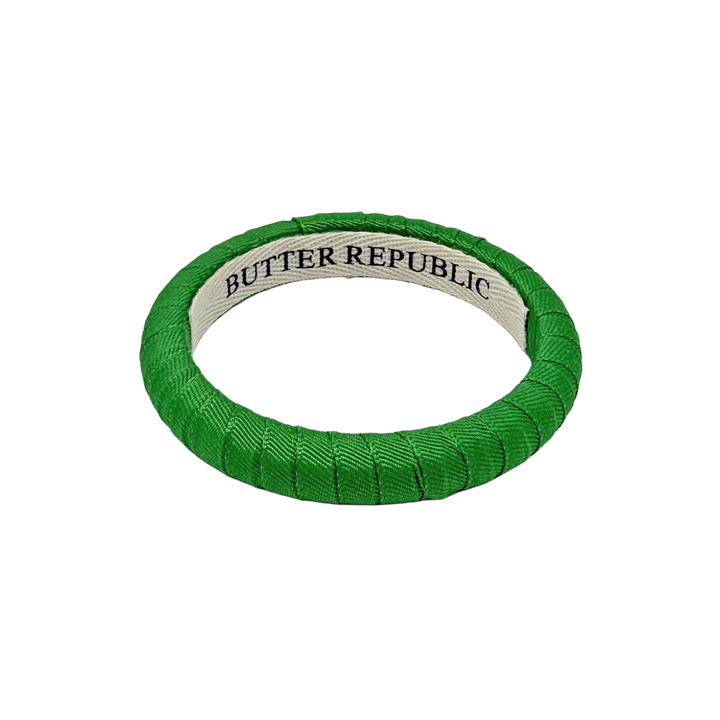 green narrow Butter Republic bracelet with a brand label on the interior of the bracelet