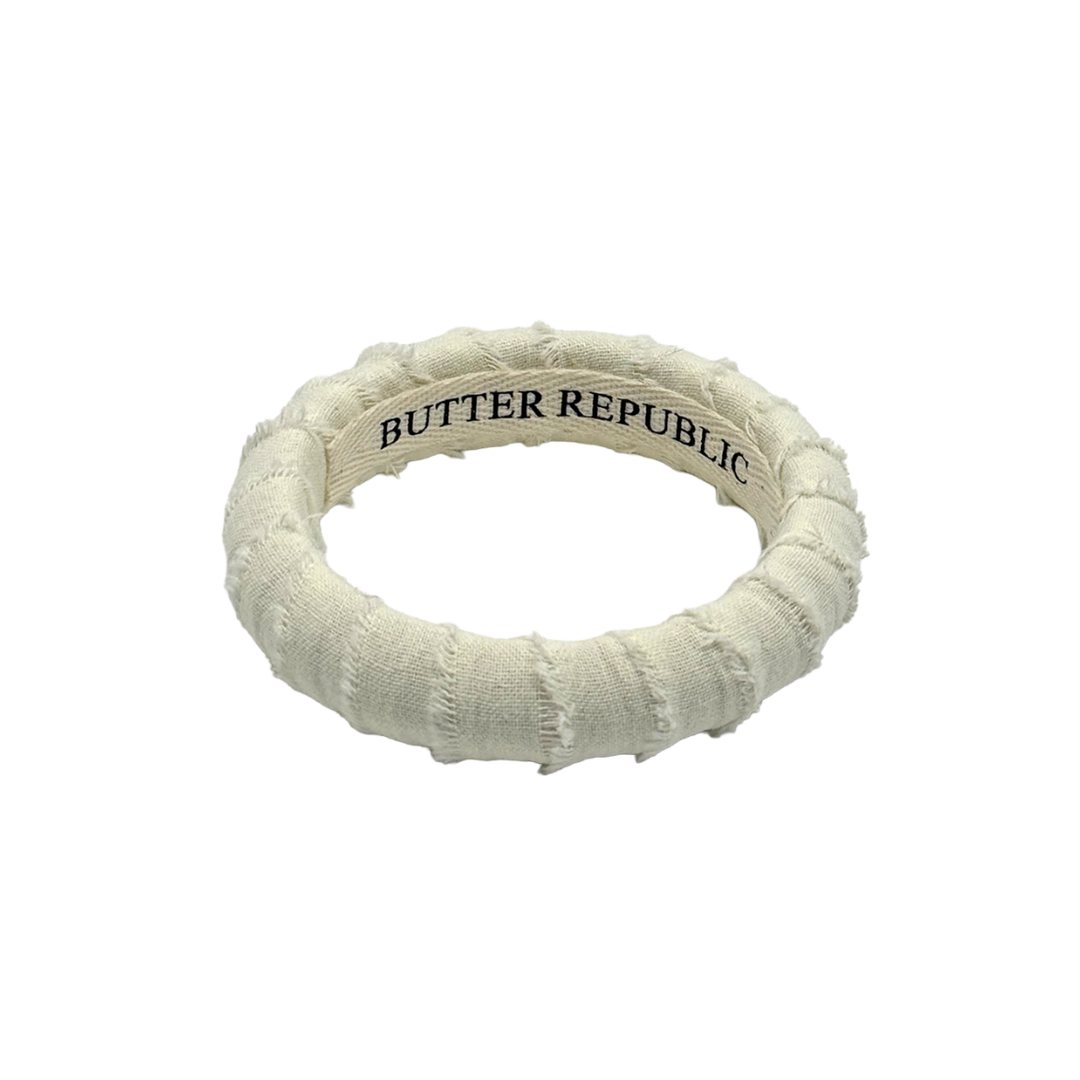 Ivory bracelet wrapped with frayed edge ribbon with 'Butter Republic' branding on the interior