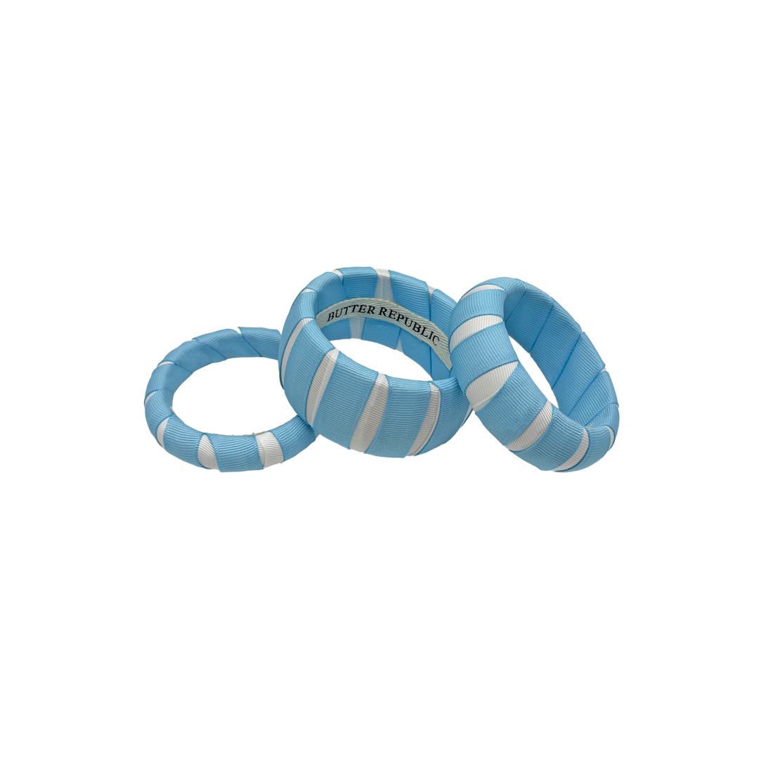 Light blue and white striped Butter Republic bracelets with brand label on the interior