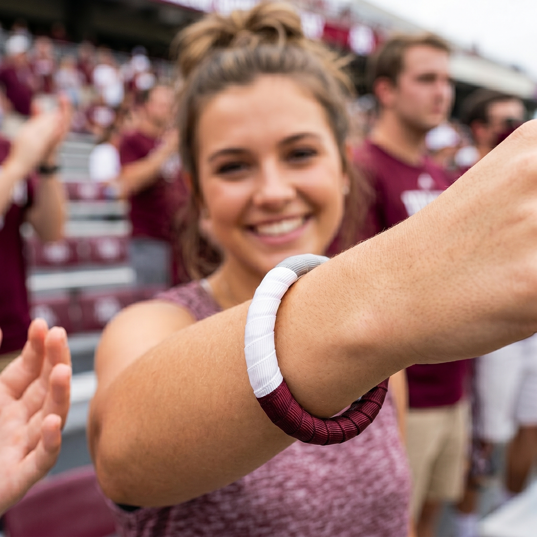 Young woman wearing a maroon and white Butter Republic bracelet in a stadium