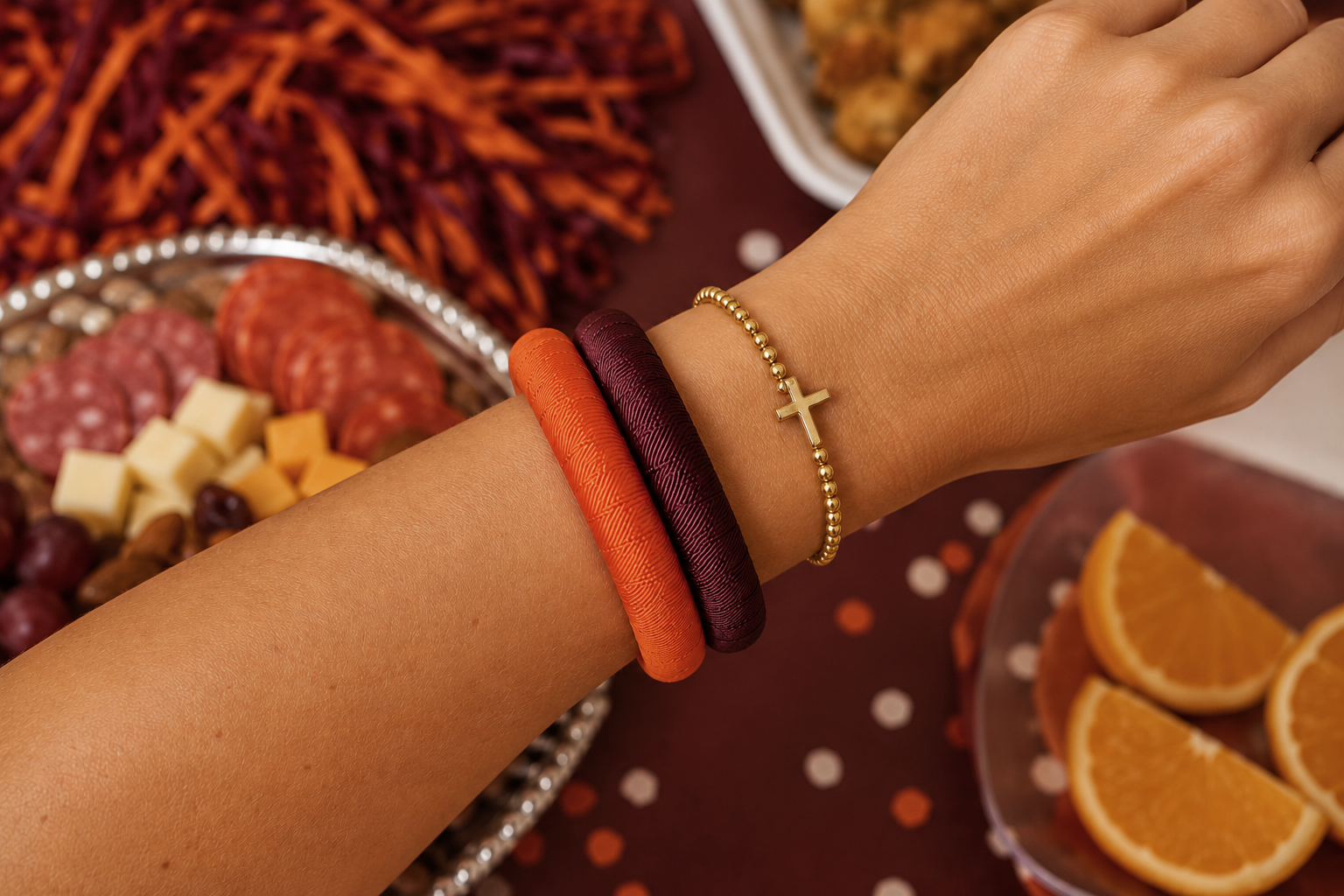 A close-up of a person's wrist wearing Butter Republic maroon and orange bracelets