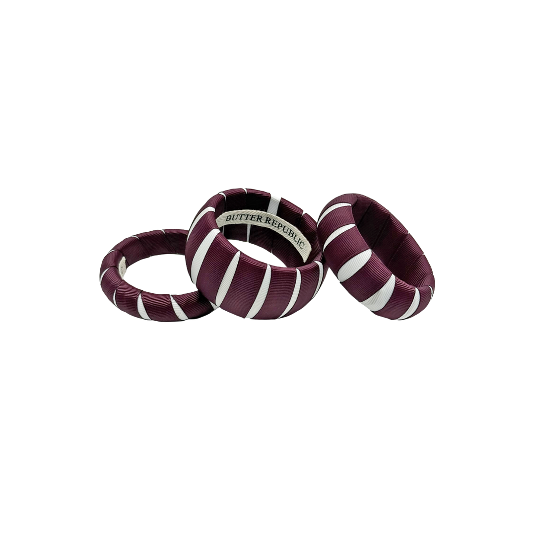 three multi-width maroon and white Butter Republic bracelets with logo brand label on the interior of the bracelet