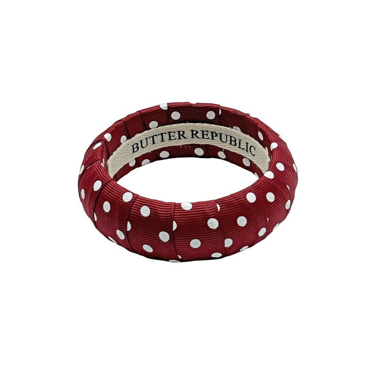 maroon and white polka dot Butter Republic bracelet with logo brand label on the interior of the bracelet