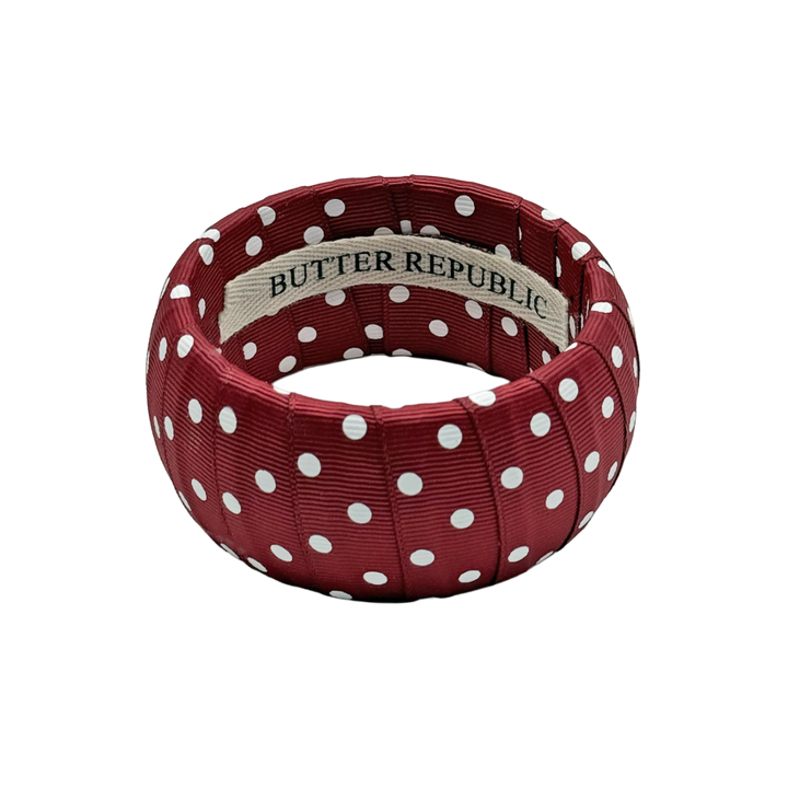 maroon and white polka dot Butter Republic bracelet with logo brand label on the interior of the bracelet