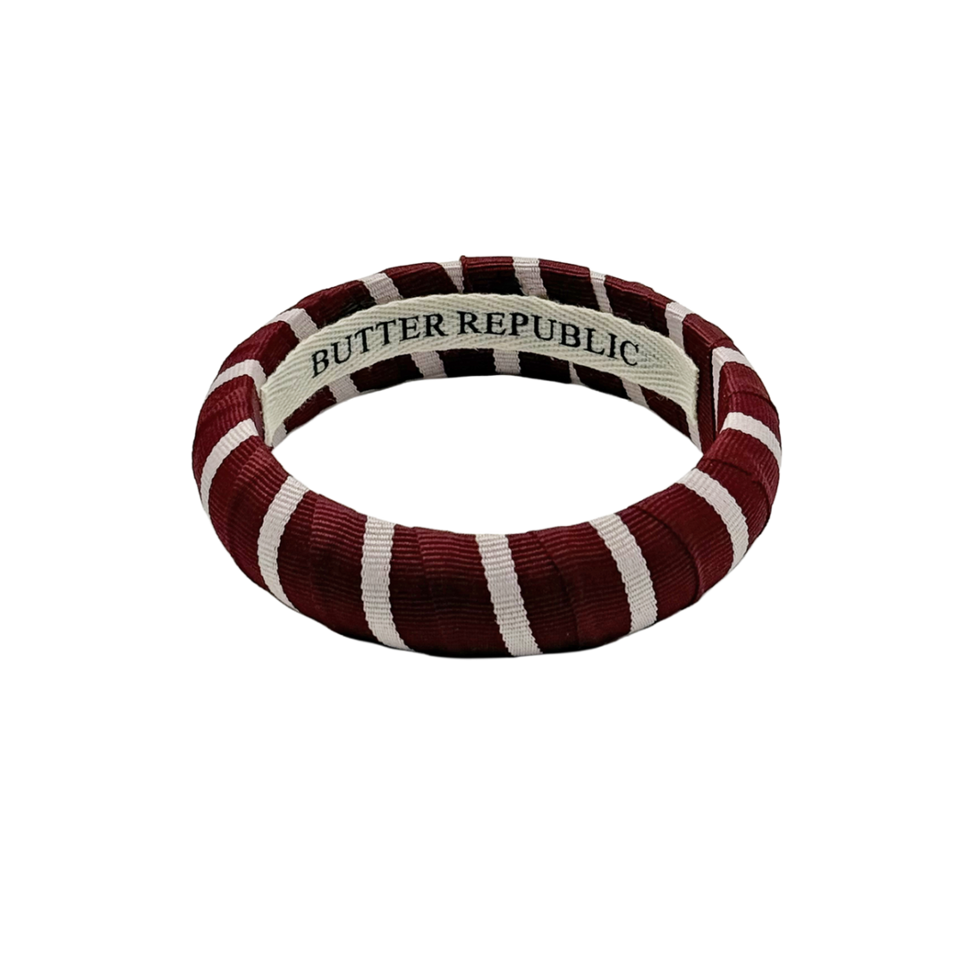 maroon and white stripe Butter Republic bracelet with logo brand label on the interior of the bracelet