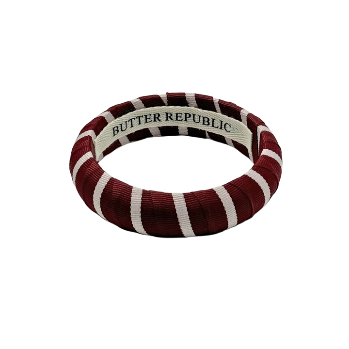 maroon and white stripe Butter Republic bracelet with logo brand label on the interior of the bracelet