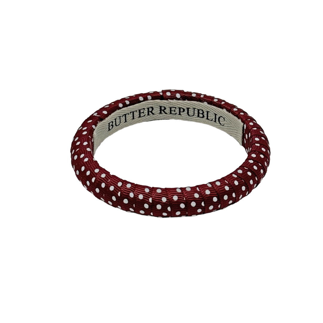 maroon and white Swiss dot Butter Republic bracelet with logo brand label on the interior of the bracelet