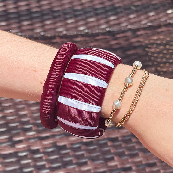 Maroon and white Butter Republic bracelets on a wrist with a woven background