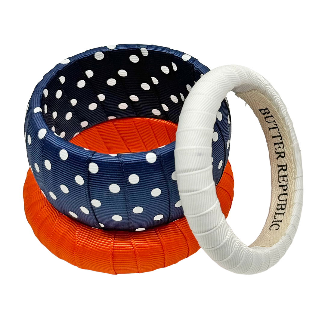 Three navy blue, orange, and white bracelets with Butter Republic brand name on the interior