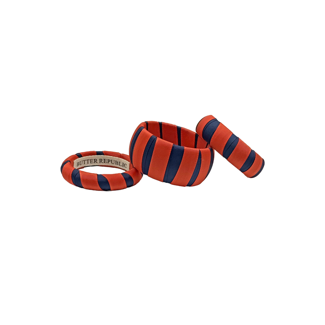 multi-width orange and navy Butter Republic bracelets with logo brand label on the interior of the bracelet