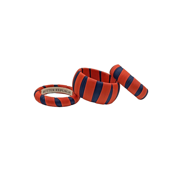 multi-width orange and navy Butter Republic bracelets with logo brand label on the interior of the bracelet