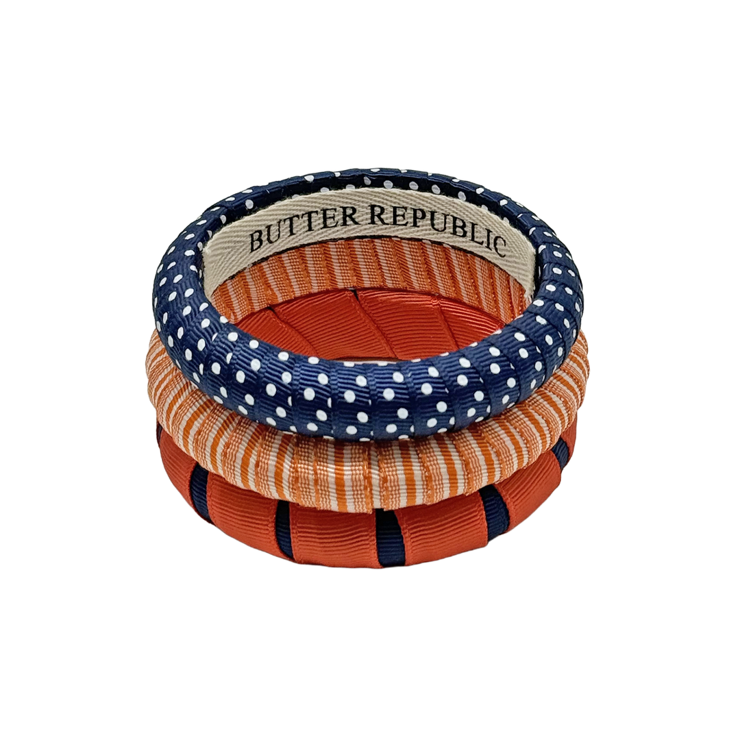 stack of three Butter Republic bracelets in navy blue and orange colors, with log brand label on the interior of the bracelet
