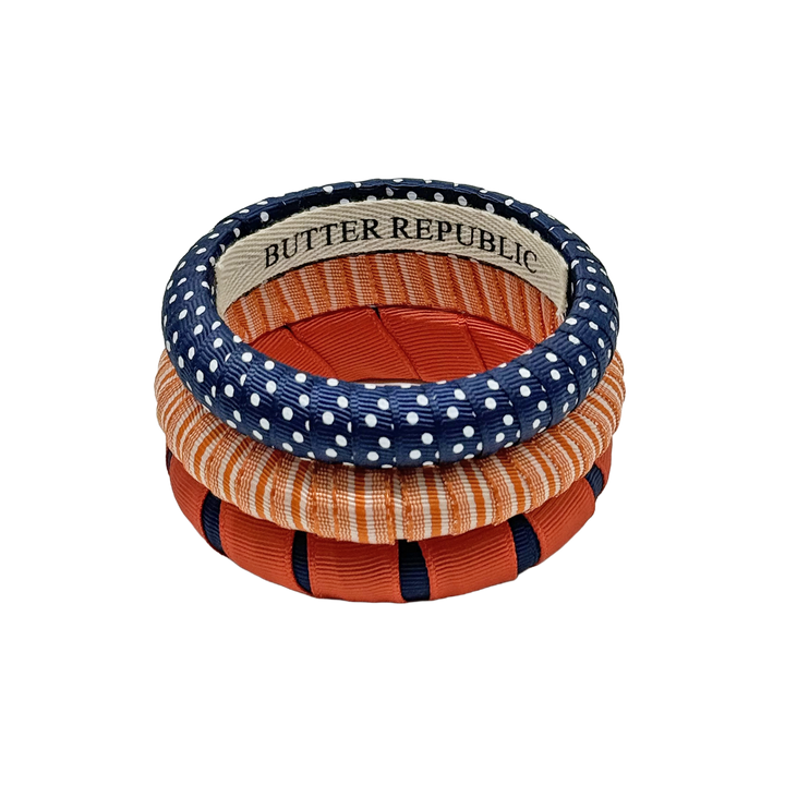 stack of three Butter Republic bracelets in navy blue and orange colors, with log brand label on the interior of the bracelet